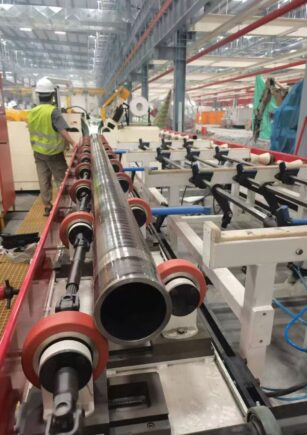 Roller-supported workpiece moving through an industrial grinding line
