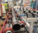 Roller-supported workpiece moving through an industrial grinding line
