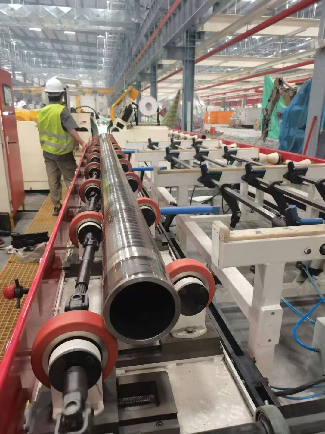 Roller-supported workpiece moving through an industrial grinding line